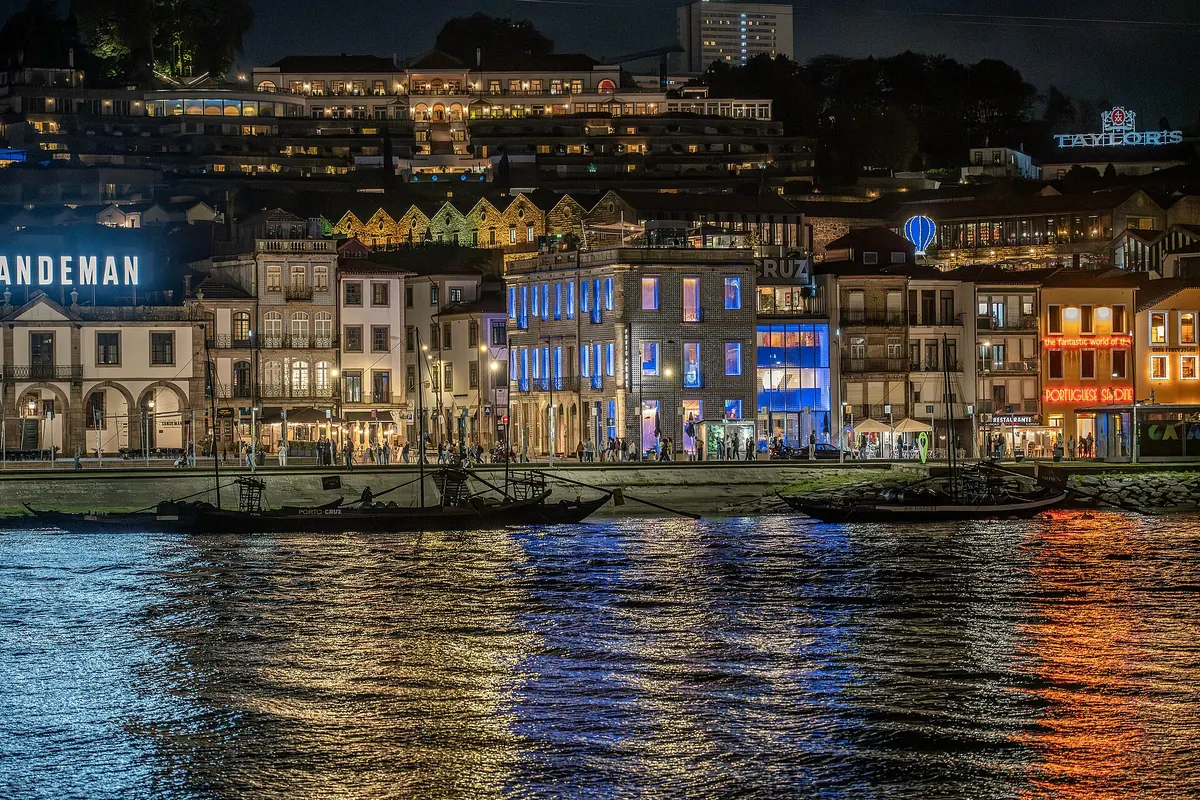 Port lodge signs and moored boats reflected in the Douro at night